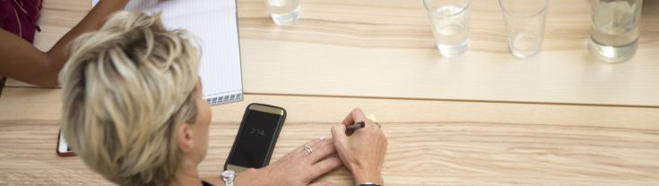 Overhead shot of a woman staking notes in a strata meeting