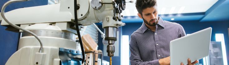 Man with laptop near machine with large drill