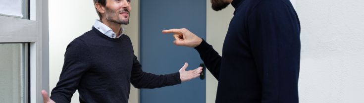 Two young men standing at a door entrance arguing with each other