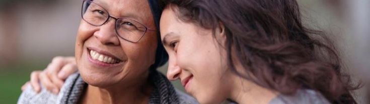 An elderly lady is hugged by her daughter