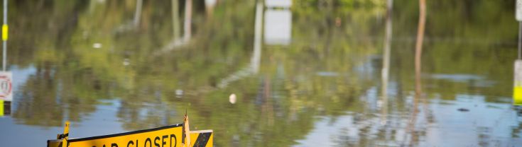 Road closed sign on flooded road.