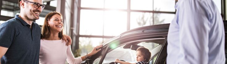 Family looking at a car and speaking to a car salesman