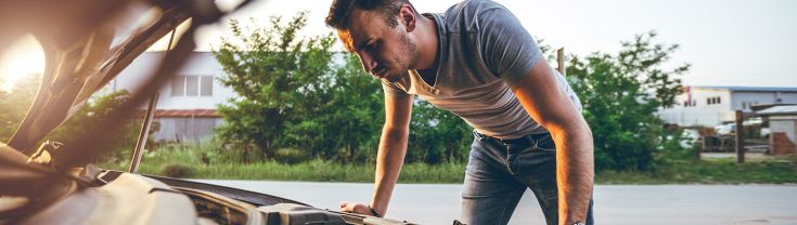 Man looking under the bonnet of a car inspecting the engine