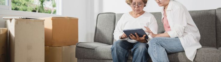 An older woman and her daughter look at a screen surrounded by boxes