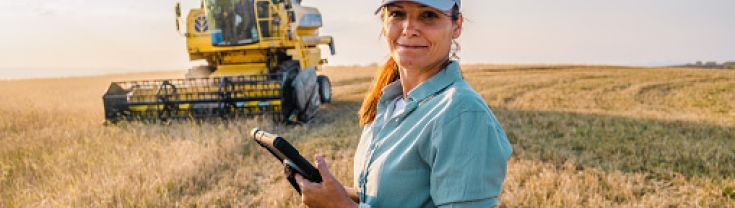 Female Farmer is Holding a Digital Tablet in a Farm Field. Smart Farming