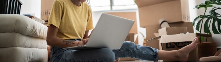 Girl with a laptop surrounded by boxes