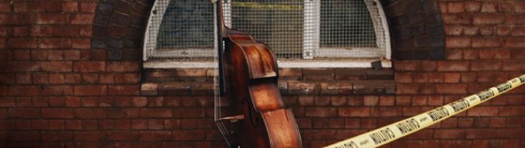 Image of cello behind yellow caution tape 