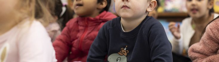 Kindergarten boy in class sat down on the floor with class mates