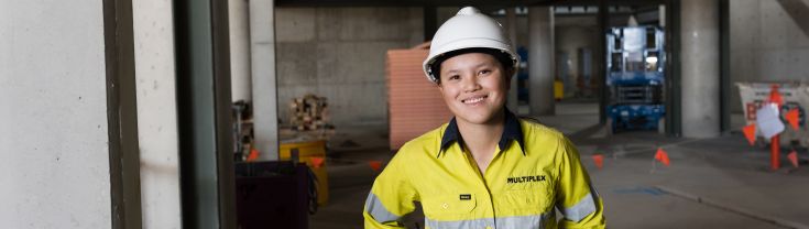 Kaitlyn on site in her construction gear, smiling at the camera.