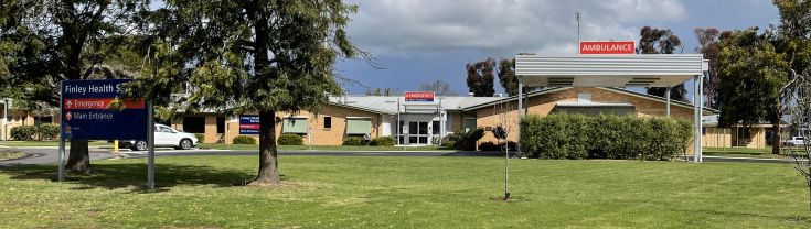 Main entry to the Finley Hospital. A sign indicating the main and emergency entry points is on the left side of the image.