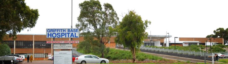 Main entry to the Griffith Base Hospital. The main entry is shown toward the left of the image, while a sign indicating the emergency driveway points toward the right of the image where a driveway is shown.