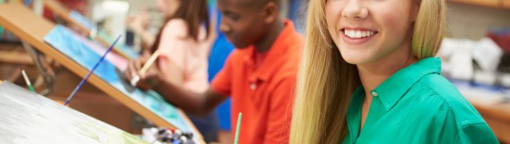 A group of four young people paint in room. A young woman with long blonde hair and a green collared shirt smiles at the camera