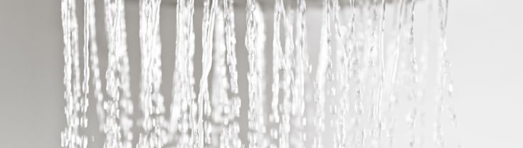 Metal shower head with water running.