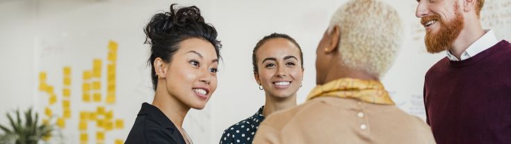 Colleagues standing in a small group discussing something while working at an office