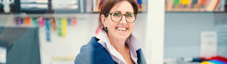 smiling female administrative worker pictured behind reception desk