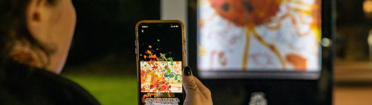 A visitor using a mobile phone while exploring the Newcastle Night Galleries interactive walking trail.