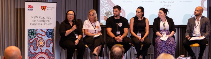 A panel of speakers on a stage talking at an Aboriginal business conference