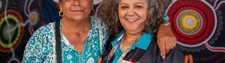 Two Aboriginal women standing side by side smiling