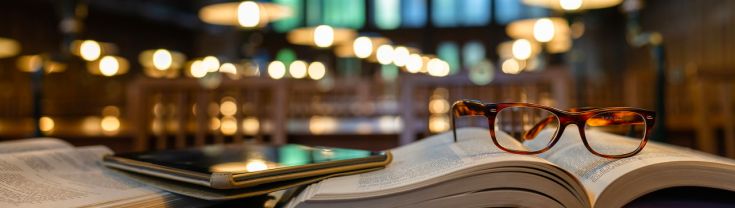 Digital tablet and eyeglasses on books in public library