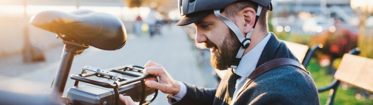 Man in helmet installing a battery on a e-bike.