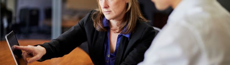 Women looking serious pointing to her laptop indicating something to colleague