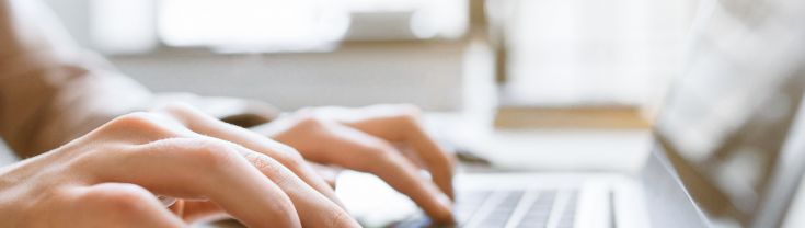 Closeup of hands typing on laptop keyboard.