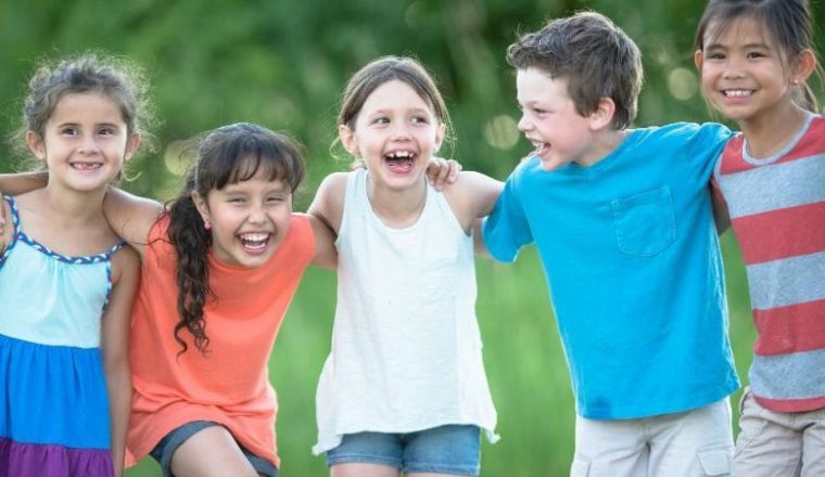 A group of primary aged children embracing each other and laughing.