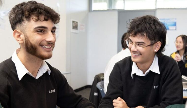 Two male high school students in class laughing