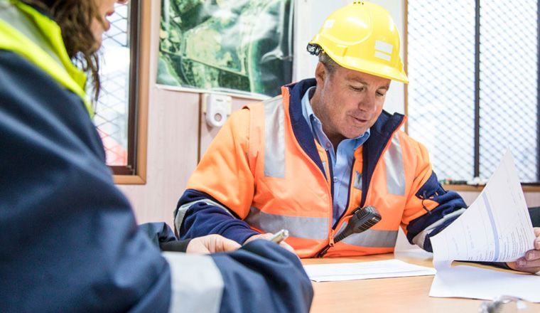 Mine manager at an office table reviewing documents