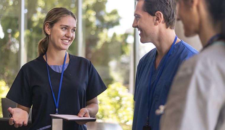 Female doctor talking to two male health professionals in wall windowed room