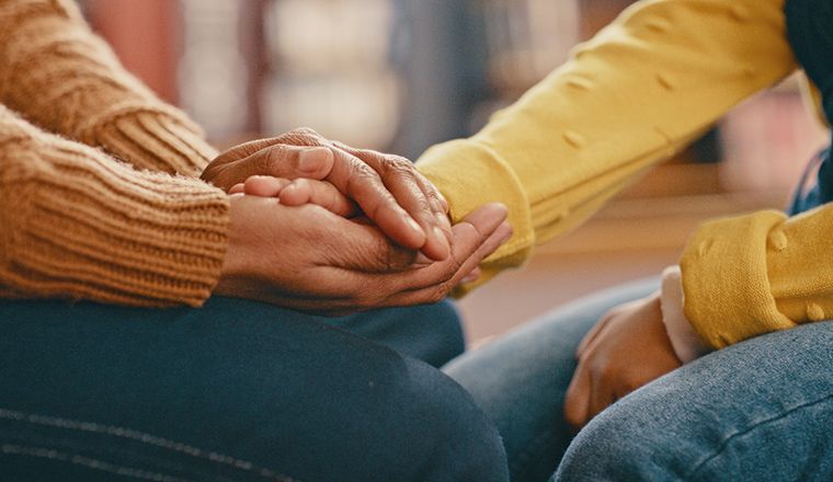 close-up of one person holding another person's hand to reassure them