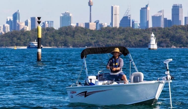 Man on boat wearing a life jacket and holding a fishing rod.