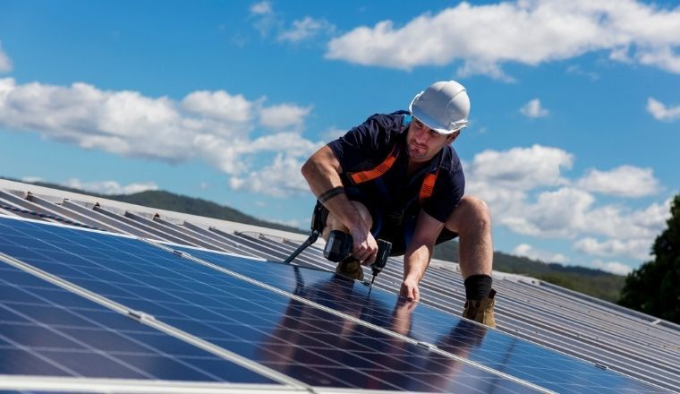 A man installing solar panels on a rooftop