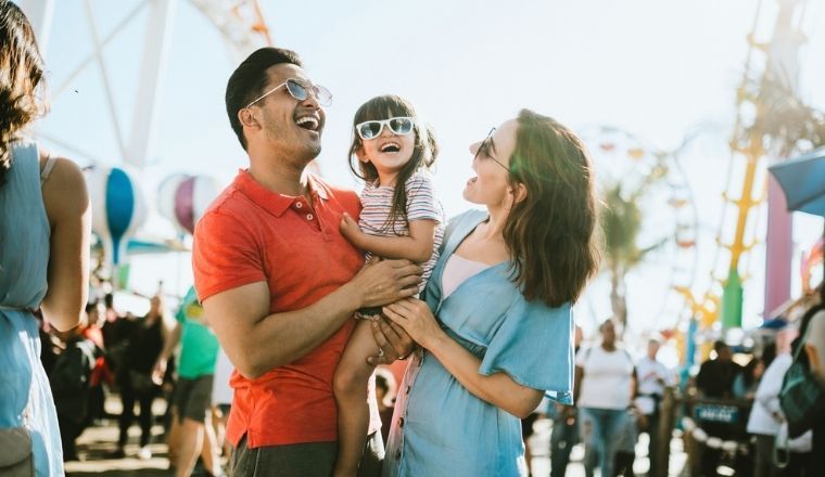 Family of 3, a mum, dad and little girl, at an outdoor carnival