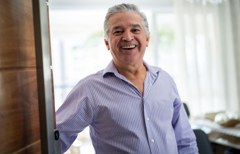 Image of a middle age man opening his front door and smiling.