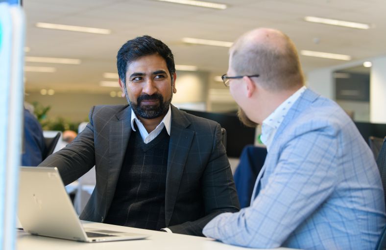 Two DCS employees talk at a desk