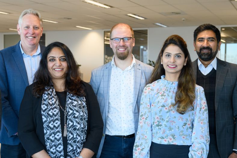 Five staff members from the Department of Customer Service standing and smiling at the camera