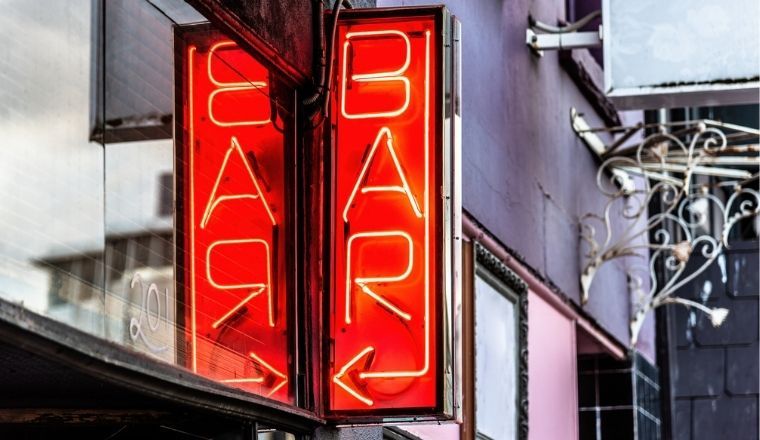 A red neon sign featuring the word BAR and a arrow pointing to the left.