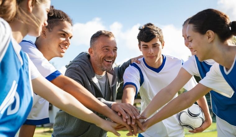 A team of young football players stacking hands before a match.