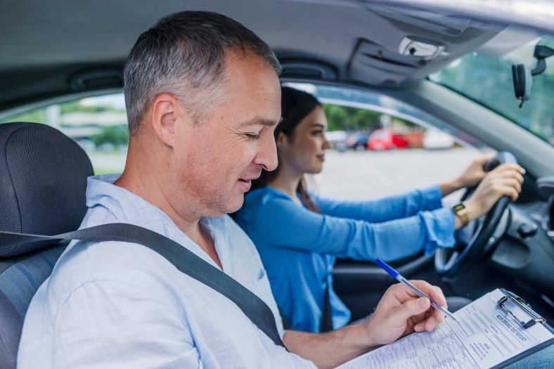 A driving test with a young woman and a testing officer in a car