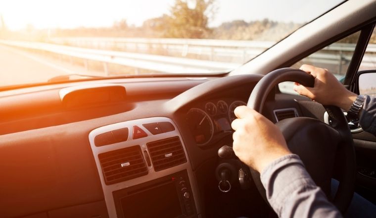 Interior of a car with a driver controlling the steering wheel.