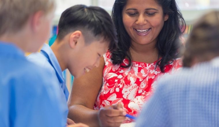 A female school teacher helping children with their work in the classroom.