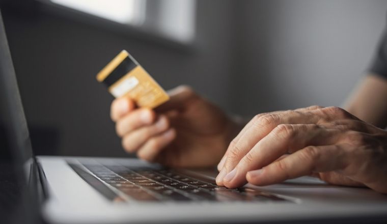 Man using a laptop with credit card.