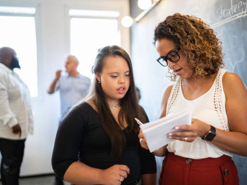 A female teachers goes over her notes with a student