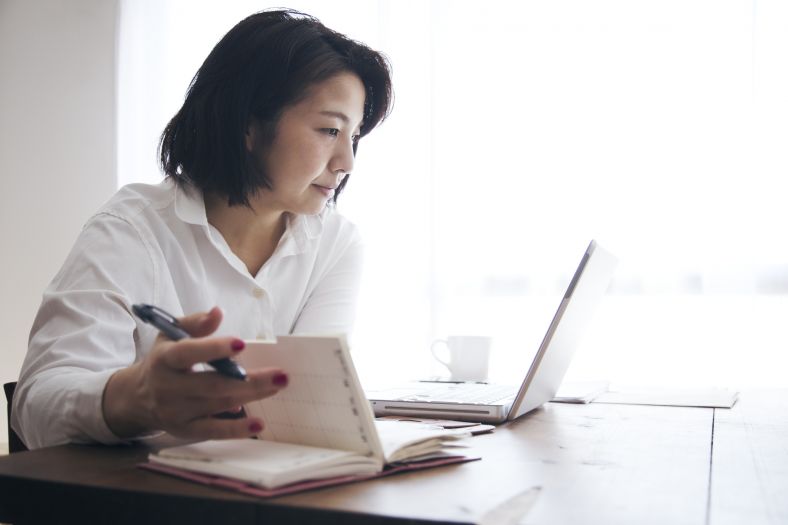 Japanese woman working from her laptop at home in a brightly lit room