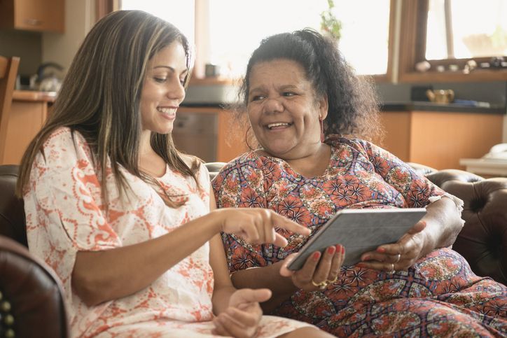 Two women using digital tablet smiling and laughing