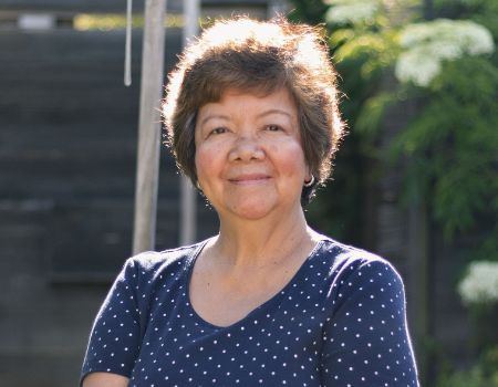 A senior lady standing outside smiling