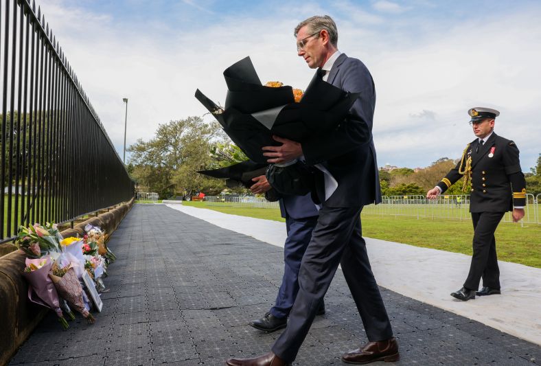 The Premier is laying flowers on the fence at Government House Sydney.