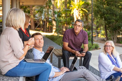 Group of workers chatting outside beside trees