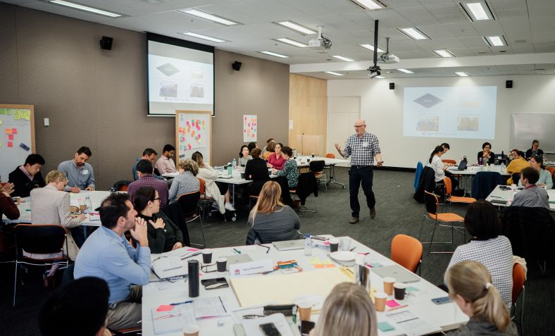 Presenter talking to crowded room of workshop participants 